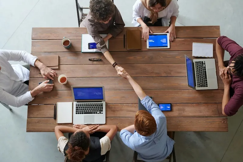 Marketing agency and client shaking hands across a table, symbolizing flexible partnership and growth